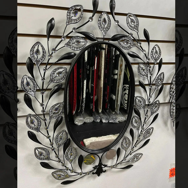 A wall-mounted oval mirror with a diamond-encrusted frame, reflecting the room around it.